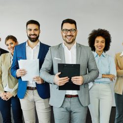 Group of young business people having a meeting or presentation and posing in the office. Portrait of a young business man and a group of young businesspeople. Startup concept